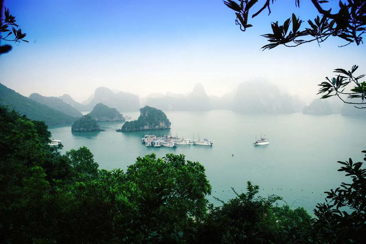 Mist falls over Halong Bay in winter creating a mysterious landscape with boats anchored in Halong Bay.