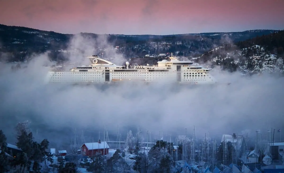 Cruise ship in dense fog in a fjord in winter. 