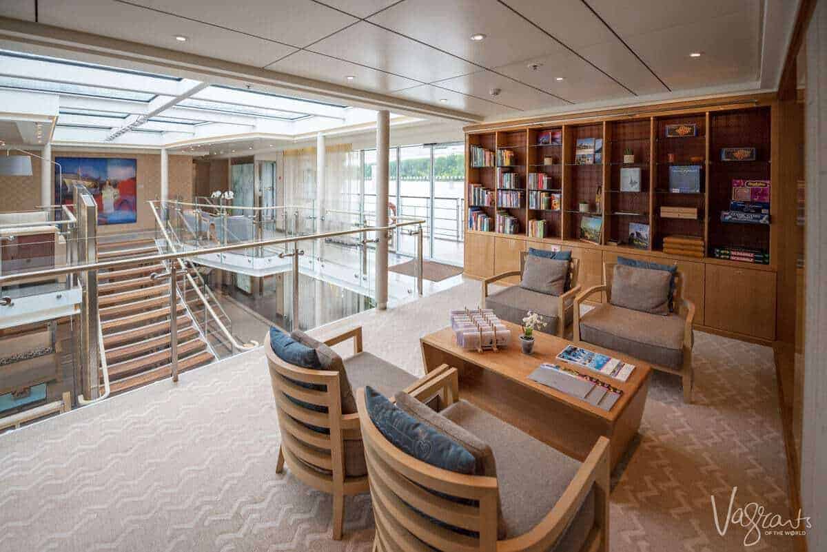 Reading and games area on a viking river cruise with shelves of books and a view of the ship's atrium in the background. 