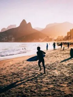 Surfer running down the beach to the water. il