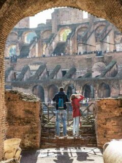 A man and women looking out over The Colosseum. How much does it cost to visit the Roman Colosseum? Read on we cover all you need to know about visiting Rome.