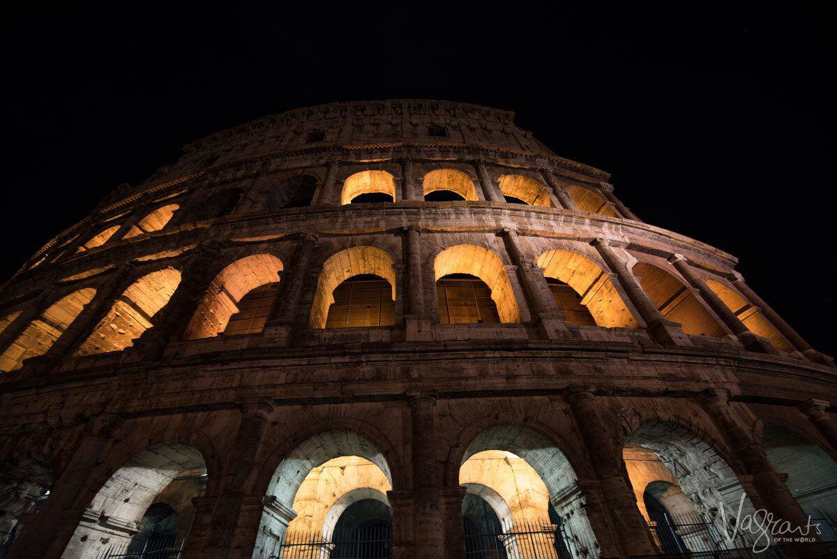 Lights shining in the arches on outside of the Colosseum at night. 