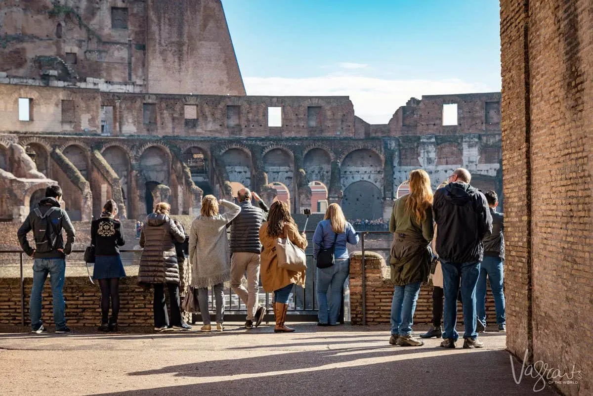 People standing looking over the Colosseum. 
