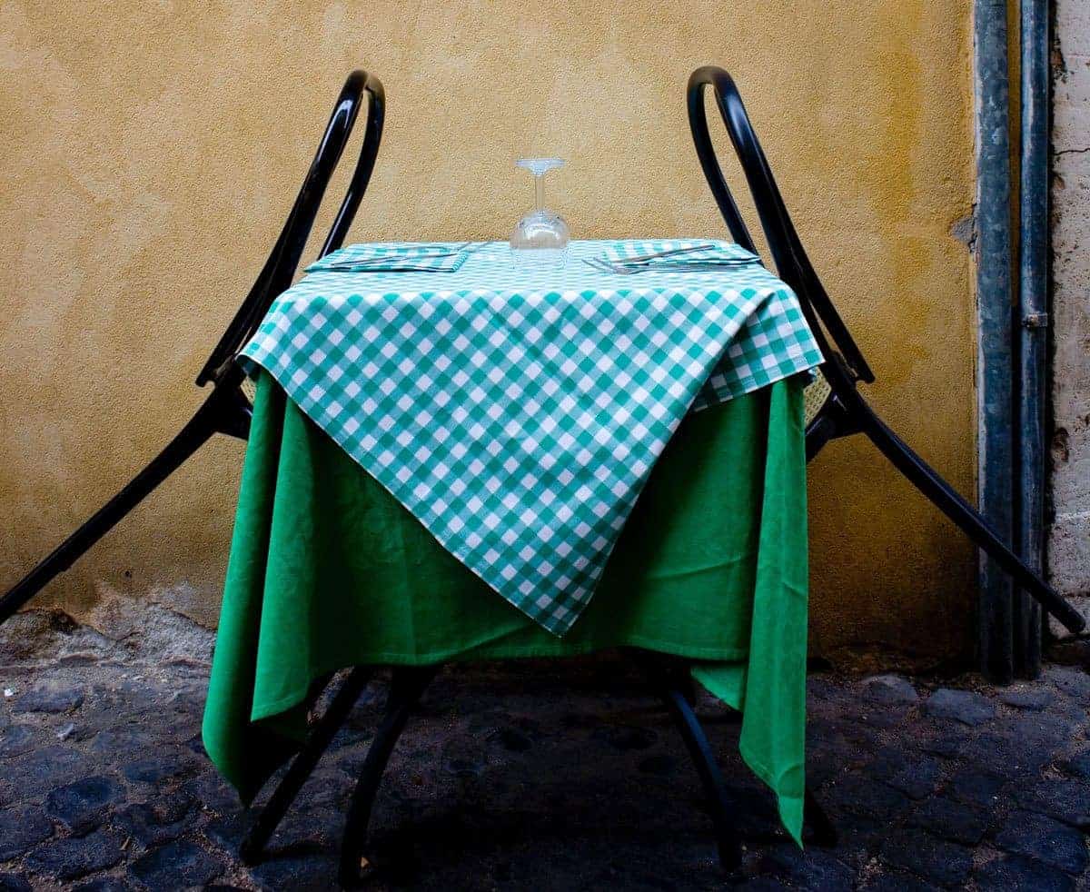 Typical Italian table with checked tablecloth and 2 chairs on sidewalk in Rome.