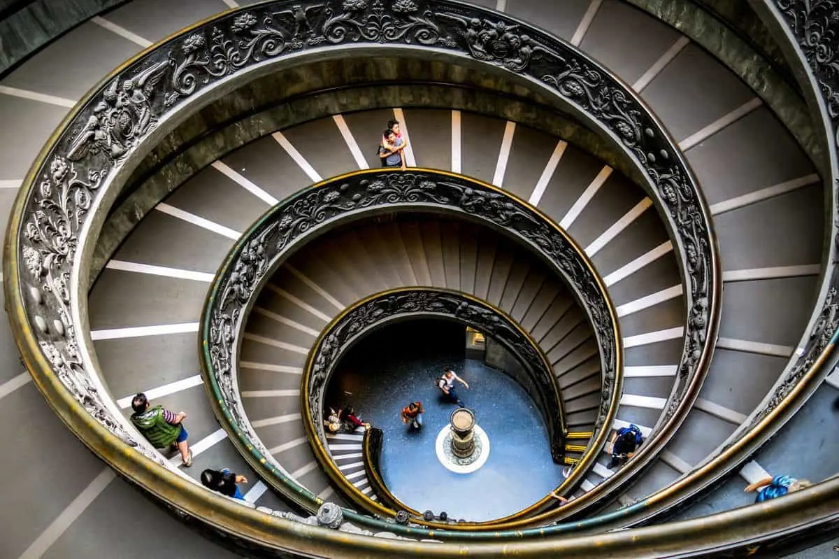 Mother hugging son on spiral staircase inside Vatican Museum. 