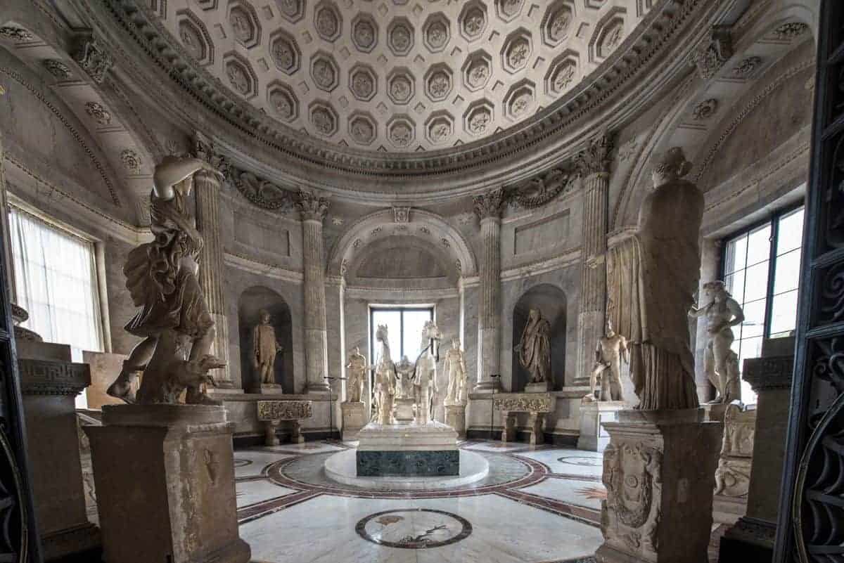 Horses and men on pedestal sculptures and circular marble floor inside Vatican Museum. 