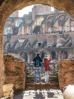 A man and women looking out over The Colosseum. How much does it cost to visit the Roman Colosseum? Read on we cover all you need to know about visiting Rome.