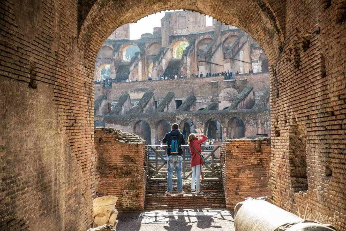 A man and woman looking out over The Colosseum in Rome Italy. 