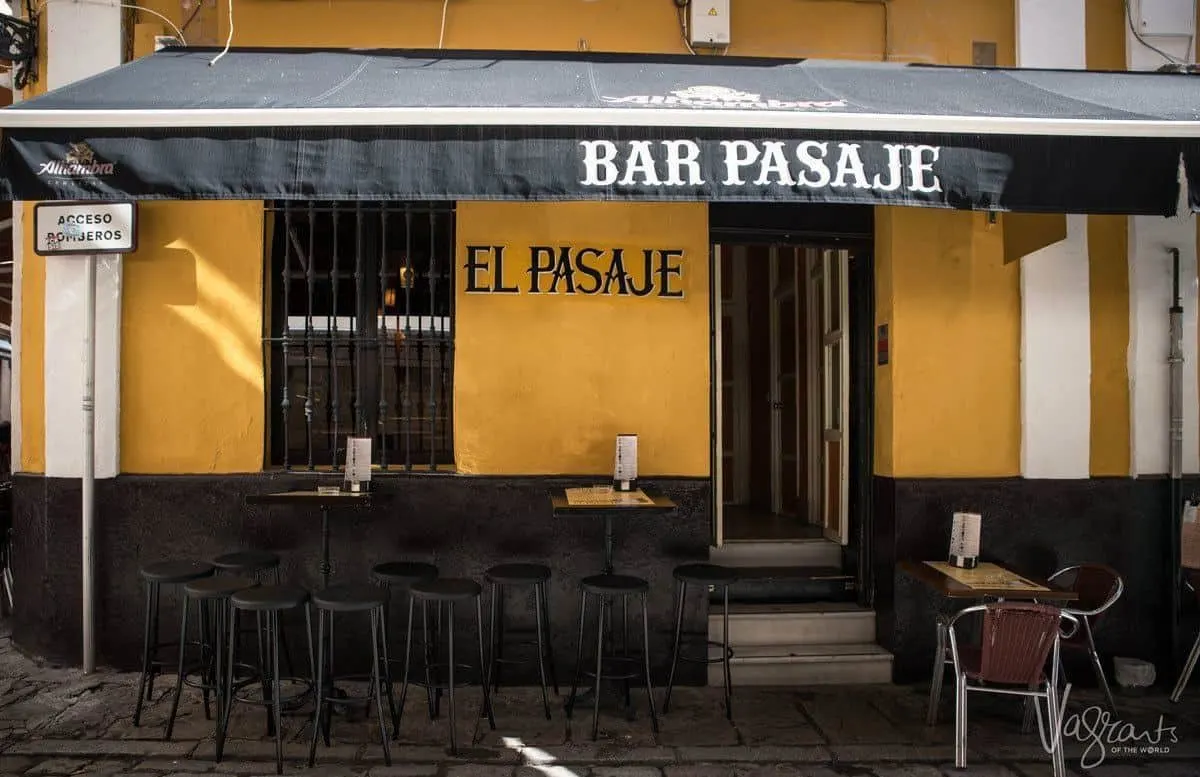 Orange and black sign of El Pasaje, a popular place to drink in seville