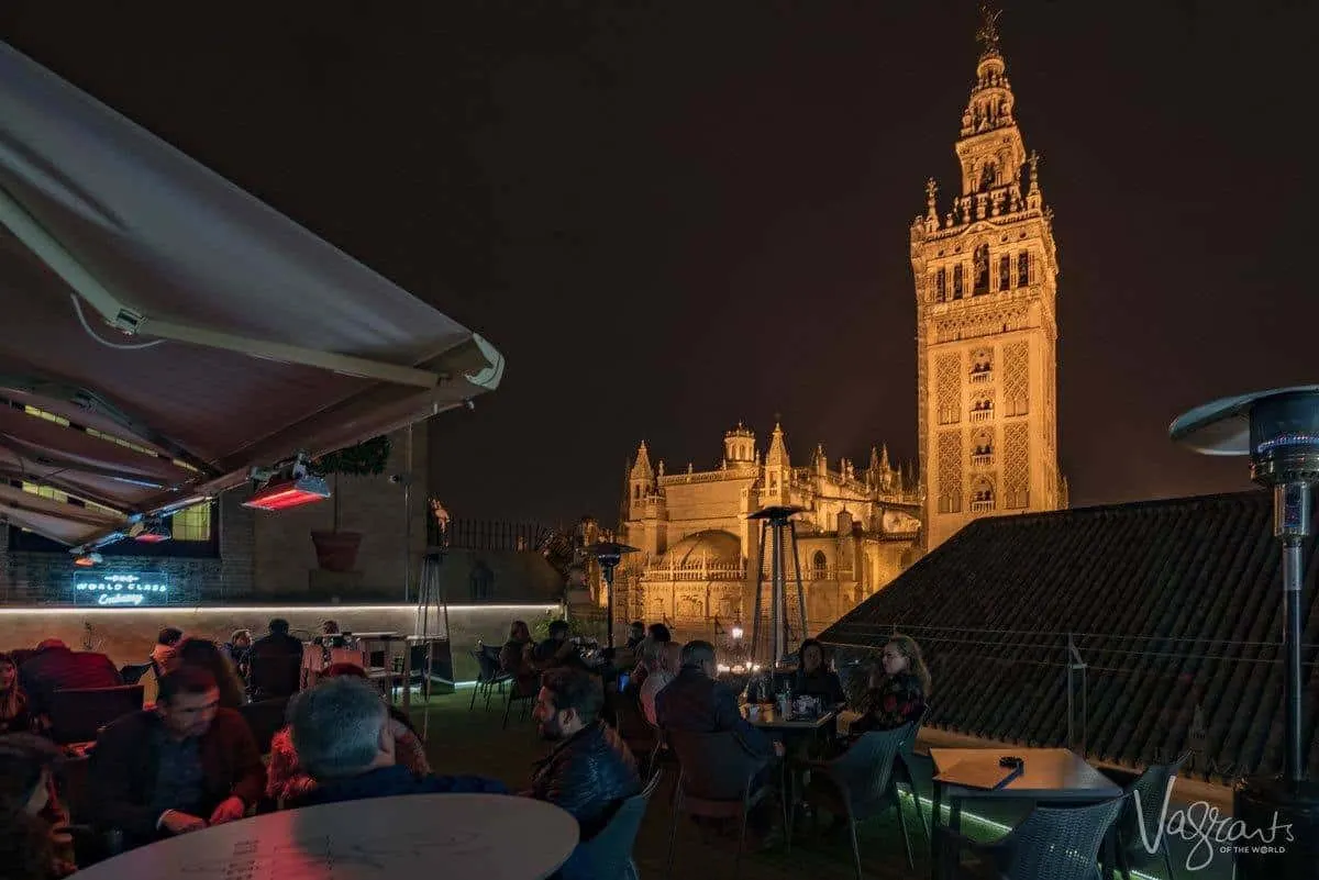 People dining at night with the Seville cathedral in the background. 