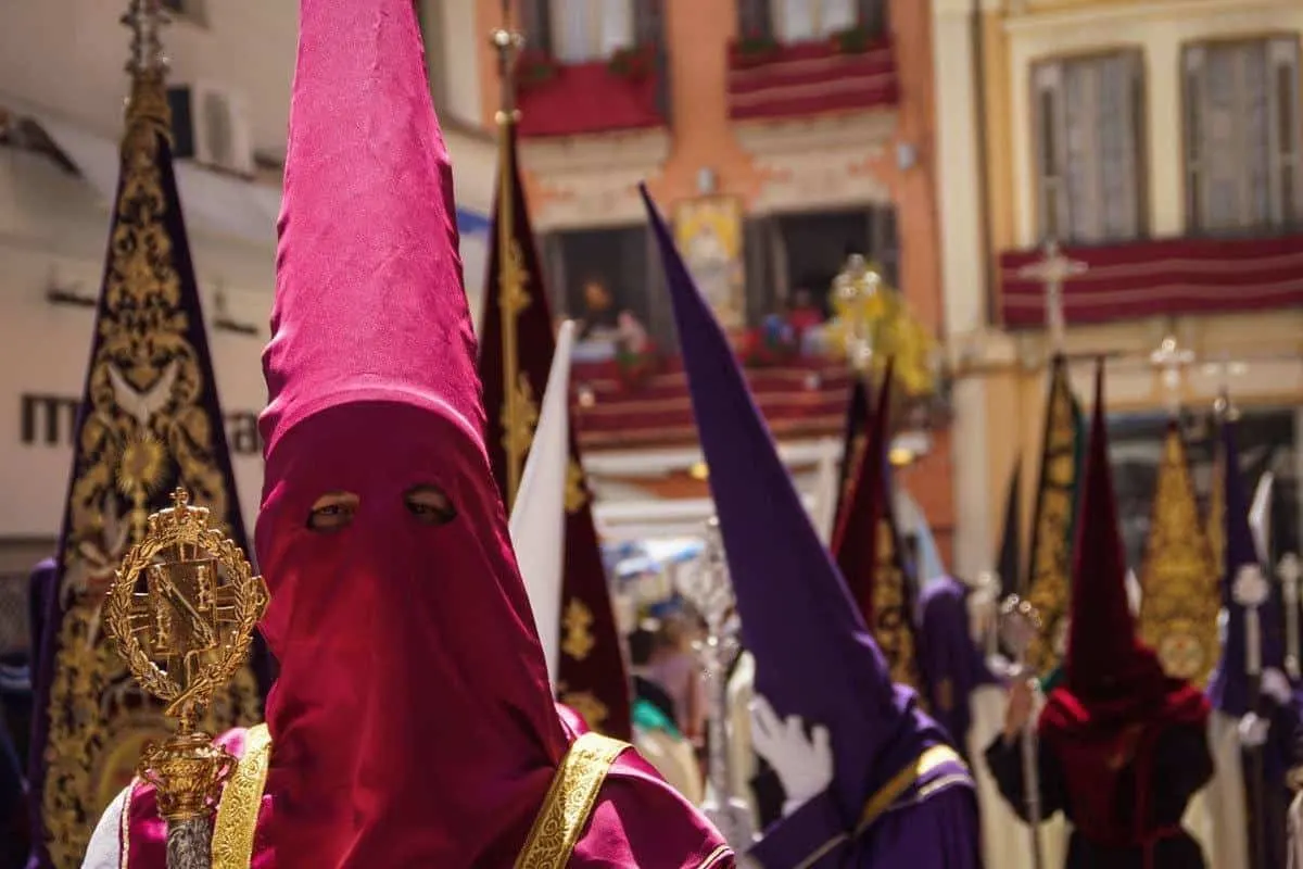 Man wearing pink hood in religious parade during Easter parade in Seville.