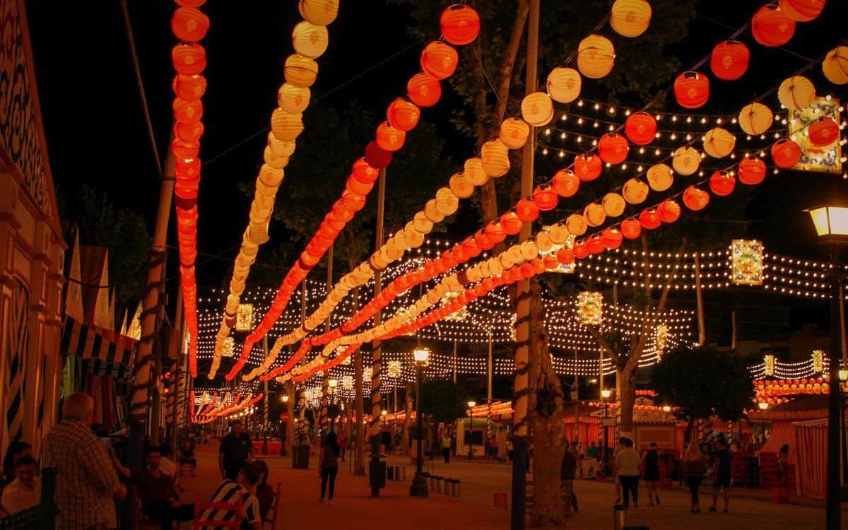 Red and yellow festive lanterns lining the street during a Spanish festival.