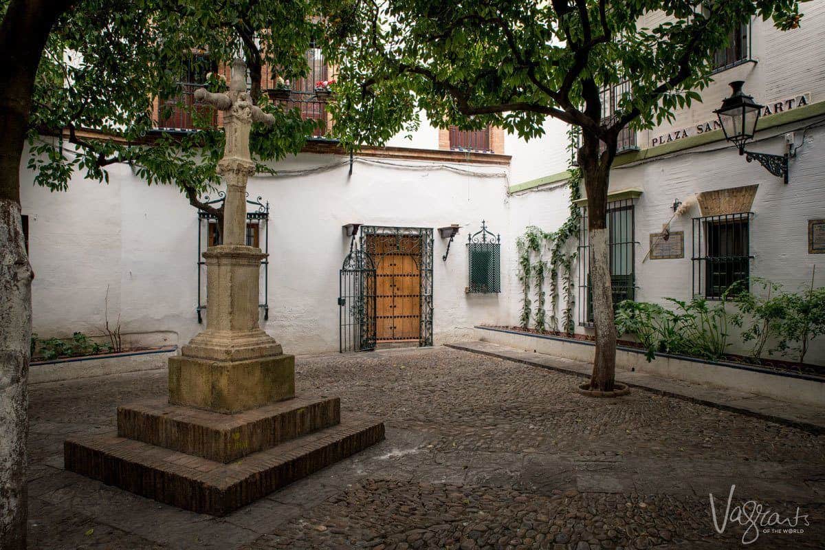 Small cross statue in Plaza Santa Marta one of the more unusual and unique places to visit in Seville.