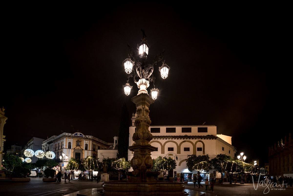 Old fashioned lit lamp post luring you out to find what Seville nightlife is all about.