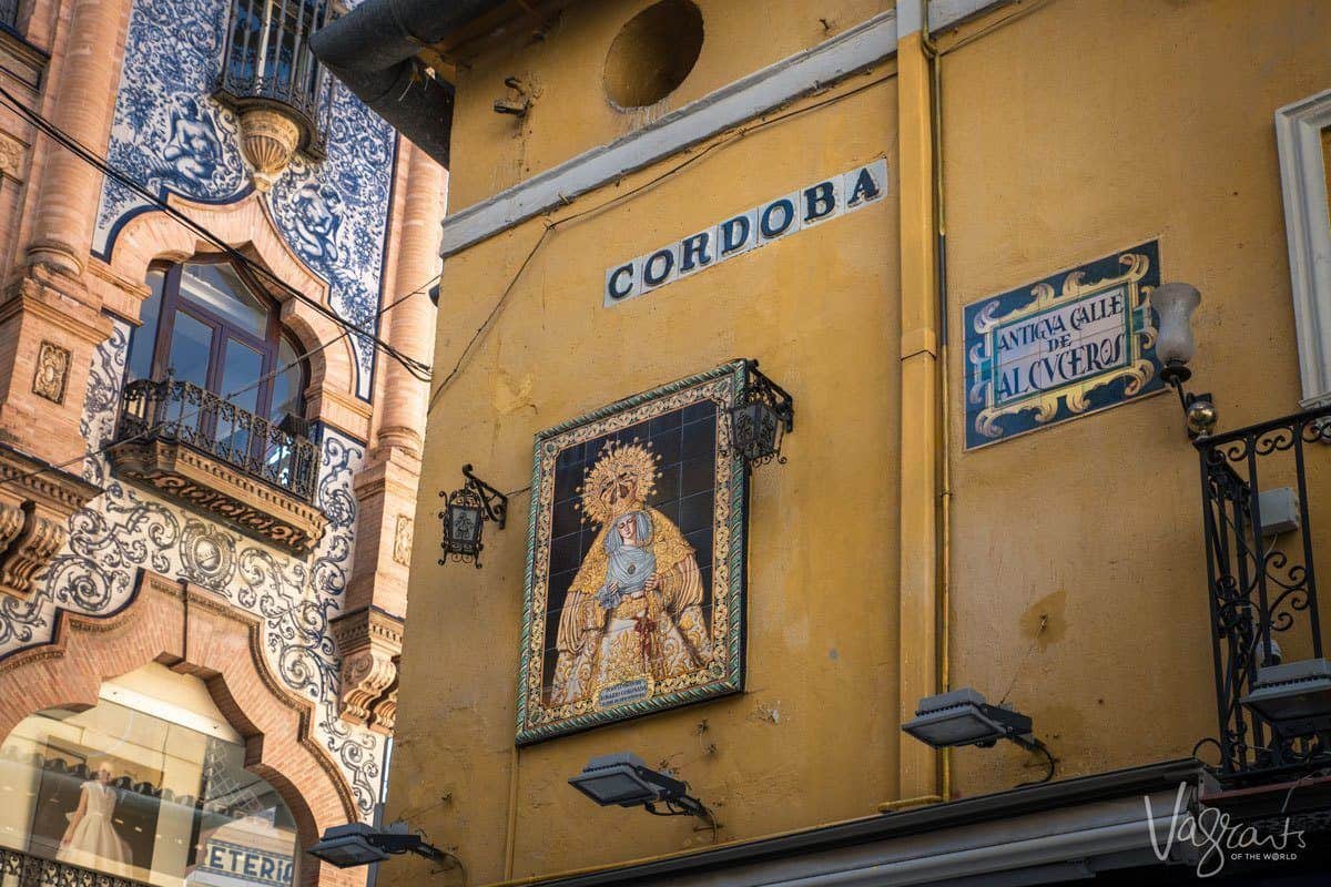 Street corner in Seville CORDOBA with religous tiled artwork on arched buildings. Apart from free things to do in Seville there are some great day trips from Seville