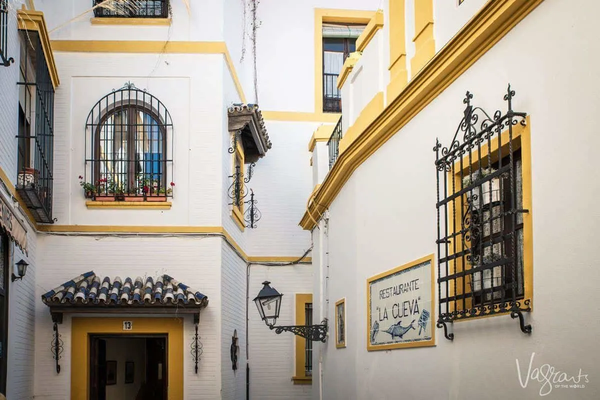 Ornate grated windows, yellow on white walls of houses in Barrio Santa Cruz in Seville. 