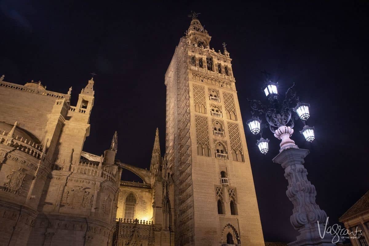 Giralda Tower and ornate street lamp at night. 