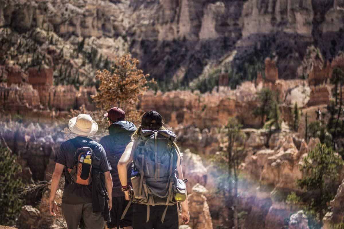 Three hikers in rocky mountains carrying sturdy day packs. 