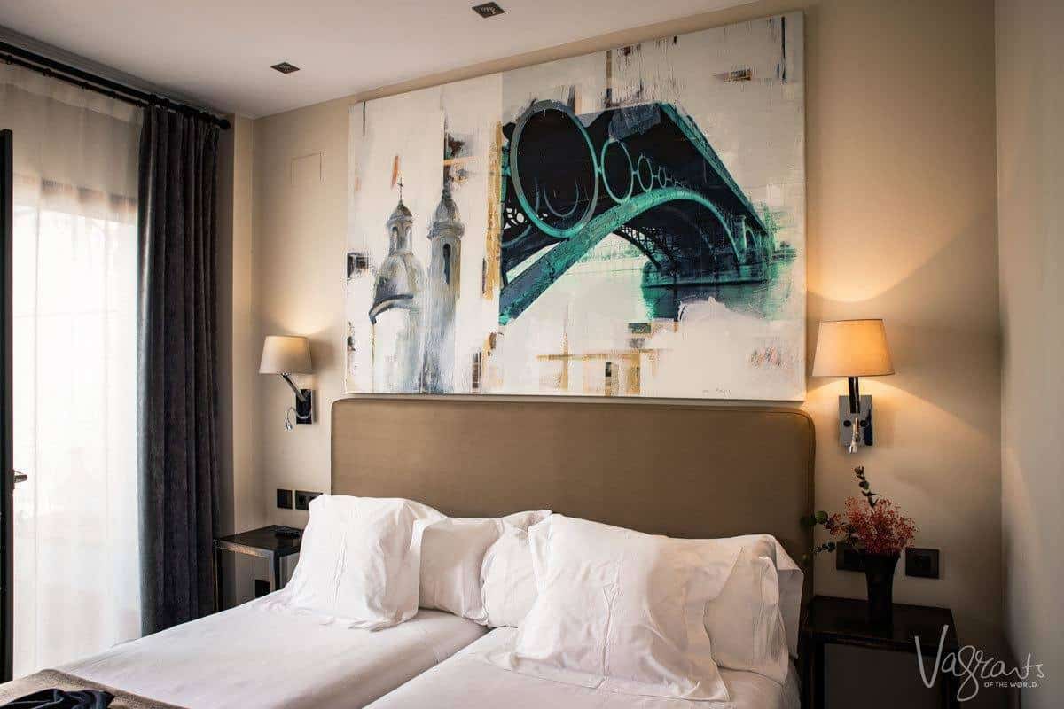 Hotel room beds with cathedral and bridge painting on a 2 or 3 day seville itinerary stay.