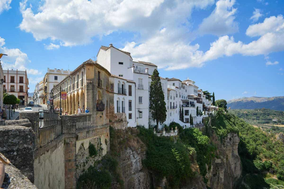 Tourist taking photos from stone bridge in Ronda. Looking for the best things to do in Ronda, it is a photographers dream and that is why you should do Day trips from Seville to Ronda