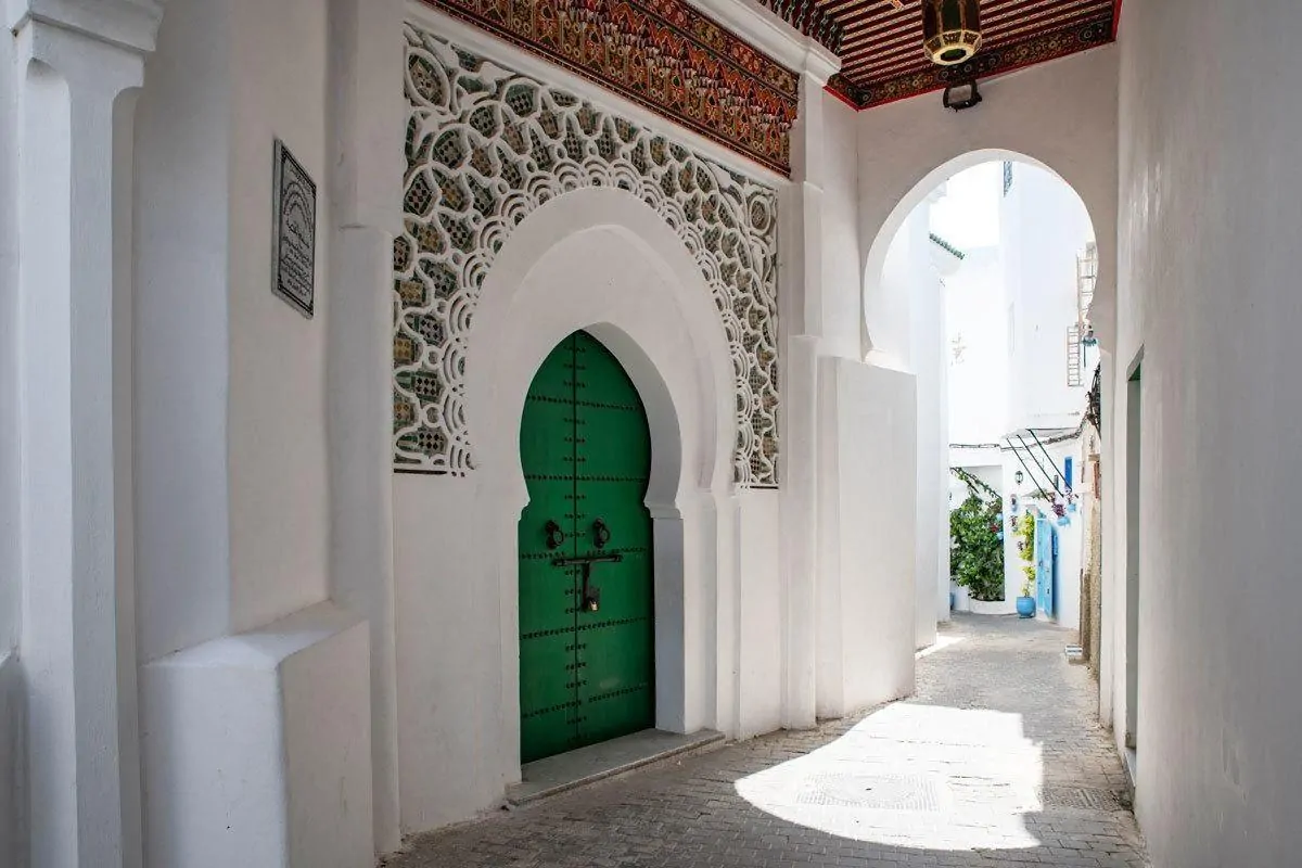 Green door set in white ornate wall in Tafira. Seeing Tafira by foot is the best free thing to do in Tangier on your Day trips from Seville to Tangier, Morocco