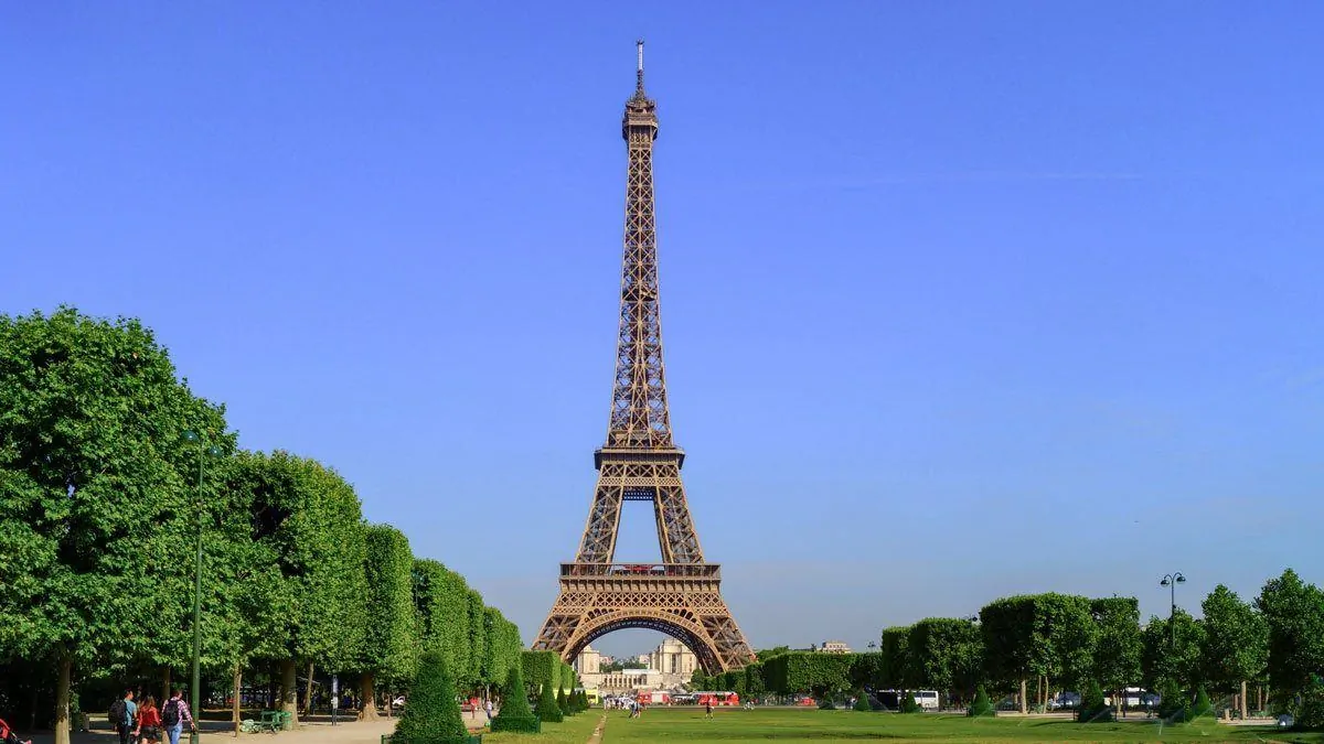 the Eiffel tower with blue skies and green trees to the side. giving thought to composition is one of the best Travel Photography Tips for Getting the Best Landmark Shots