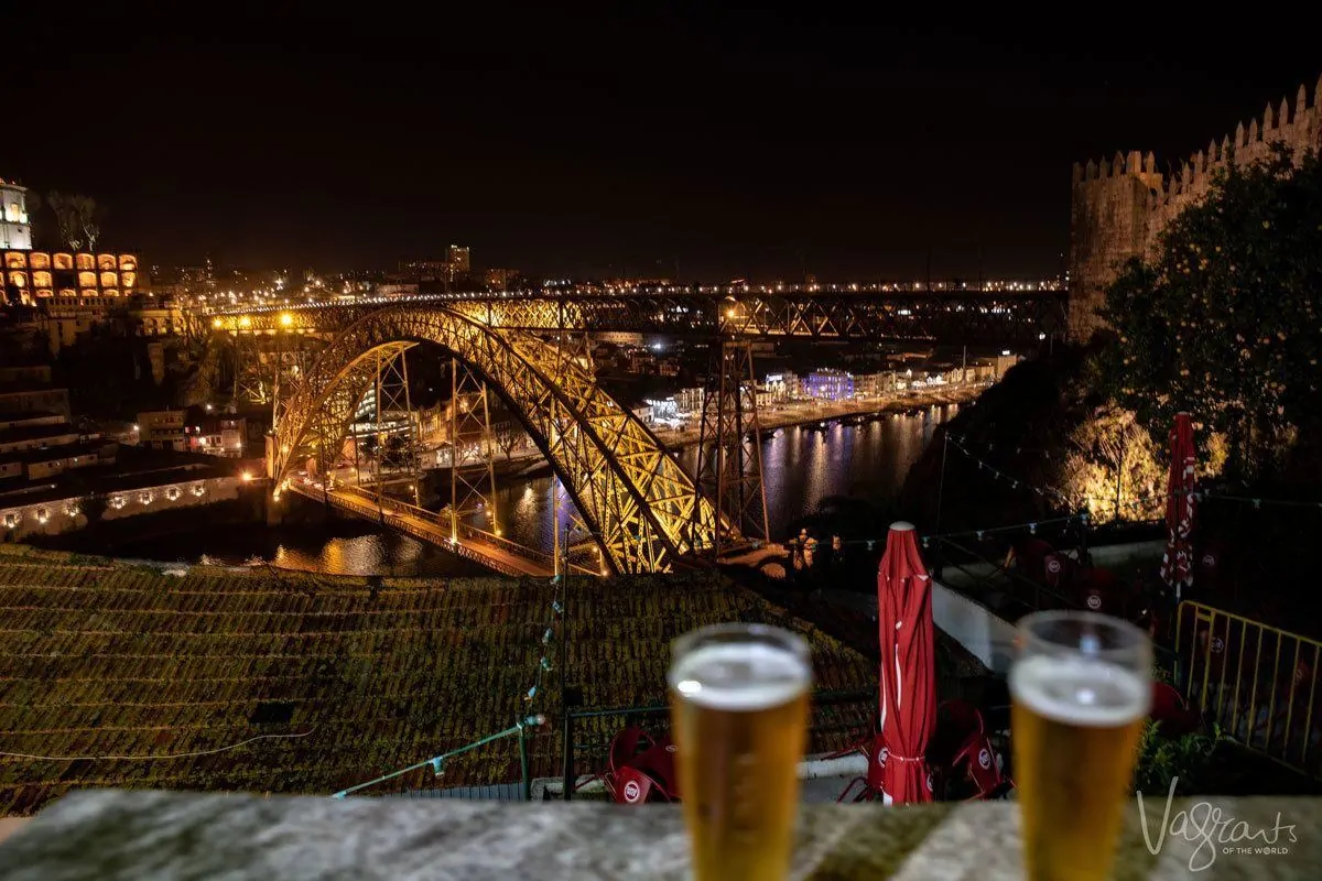 Beers with a view of the lit bridge and Douro River  at night from the beer garden at Guindalense Football Club. 