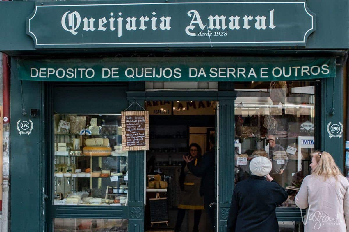 Two people admiring the cheese in the window of Queijaria Amaral Porto's oldest cheese shop. 