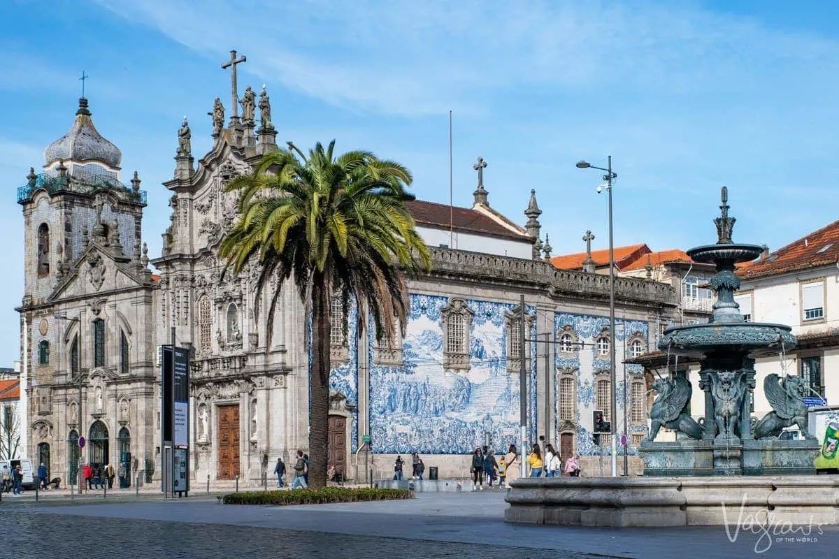 Fountain with the blue tiled wall of Igreja do Carmo and palm tree in background in Porto. 