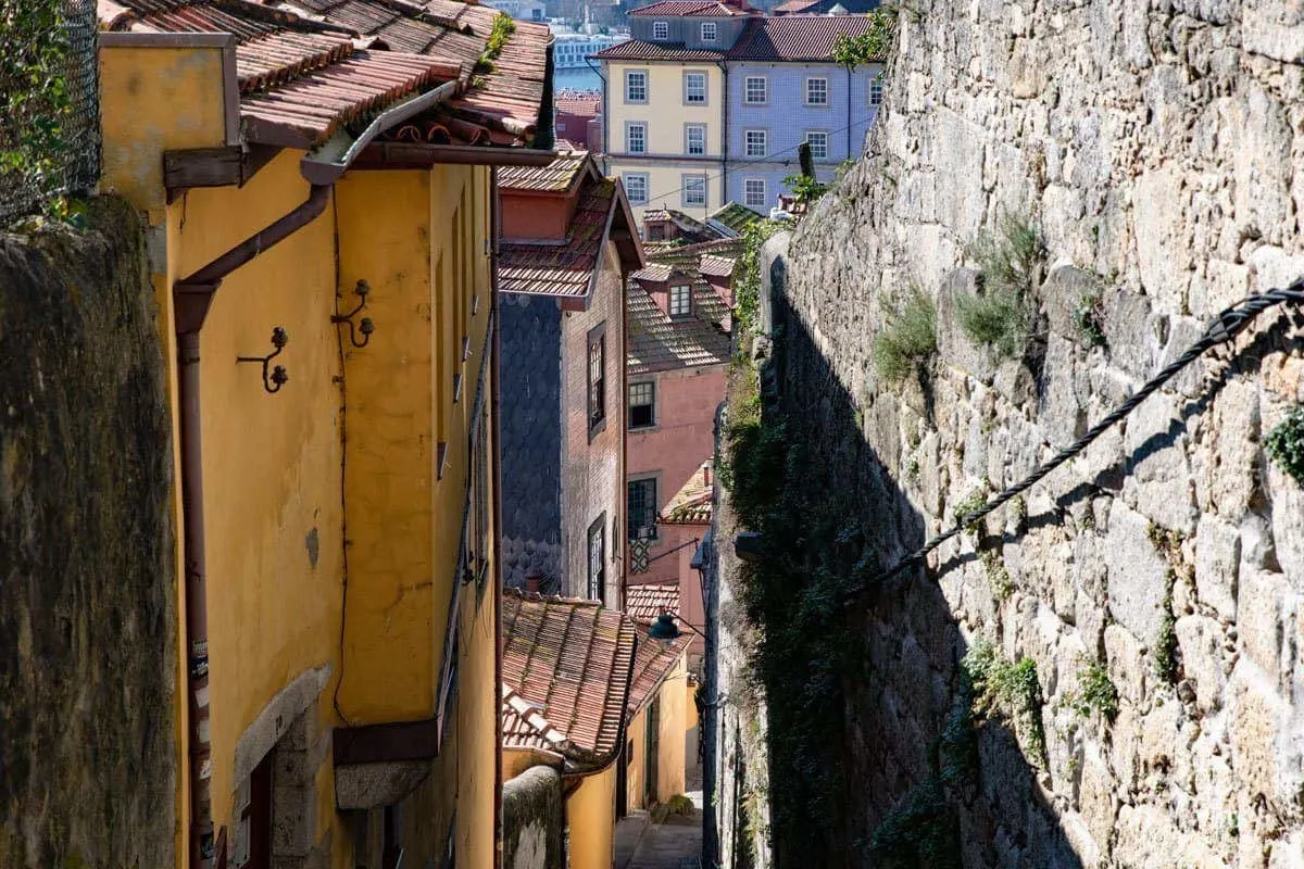 Steep stairs flanked by stone walls and ancient yellow houses in Porto. 