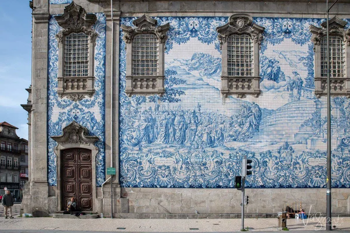 Person sitting on the steps of the blue and white tiled Igreja do Carmo. 