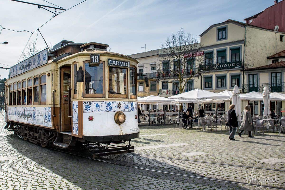 The historic tram 18 Carmo in front of an outdoor cafe in Porto. 