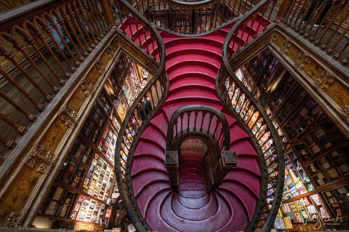 Looking down the red spiral staircase with book shelves either side in Livraria Lello Bookshop in Porto. 
