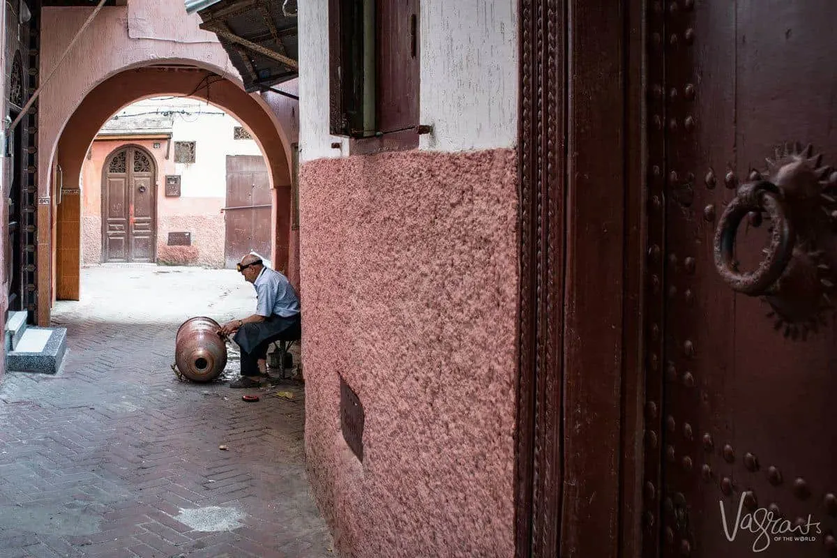 Man in alley working on copper drum in medina, Fez.
