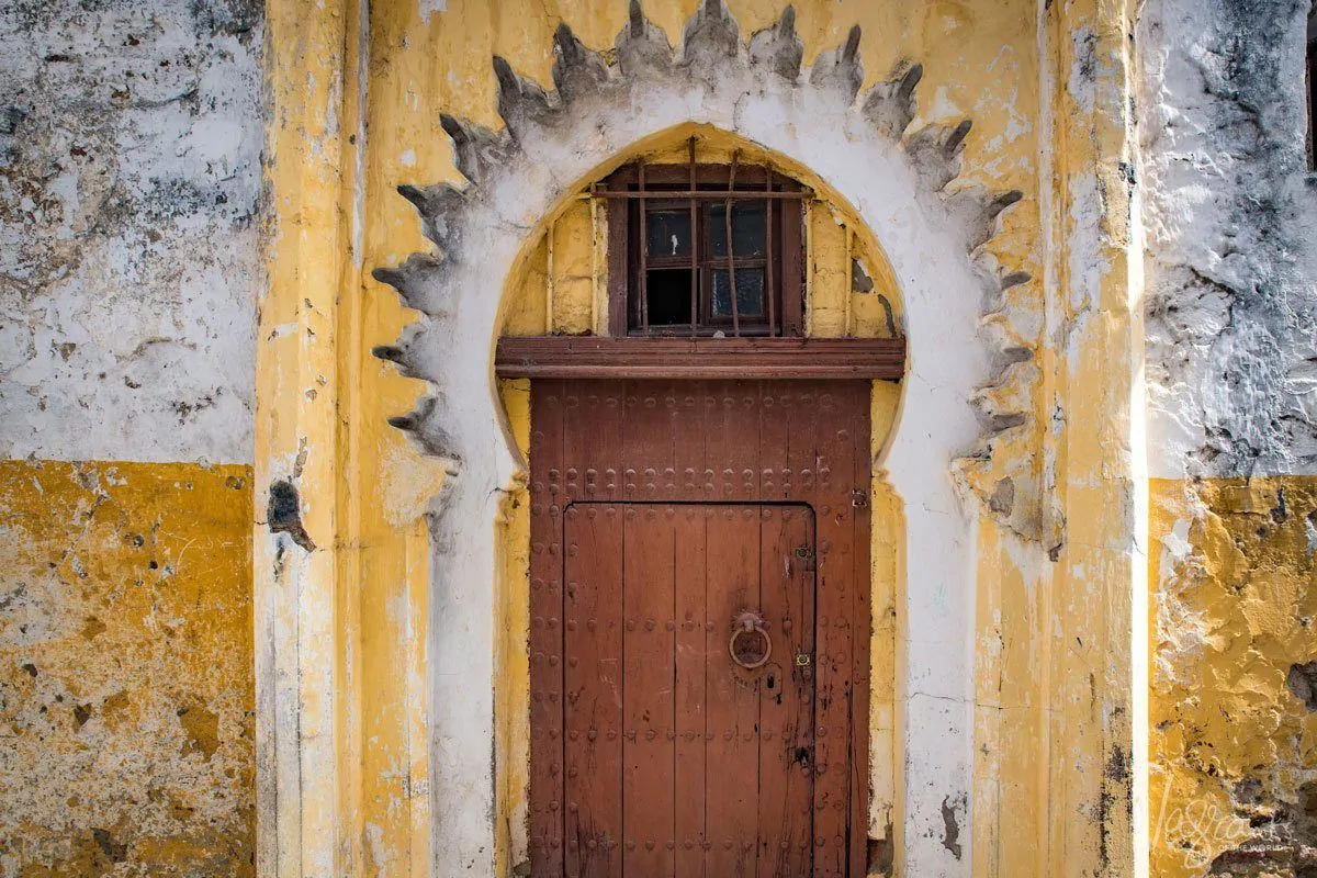 Old wooden door behind sunflower shaped yellow archway. 