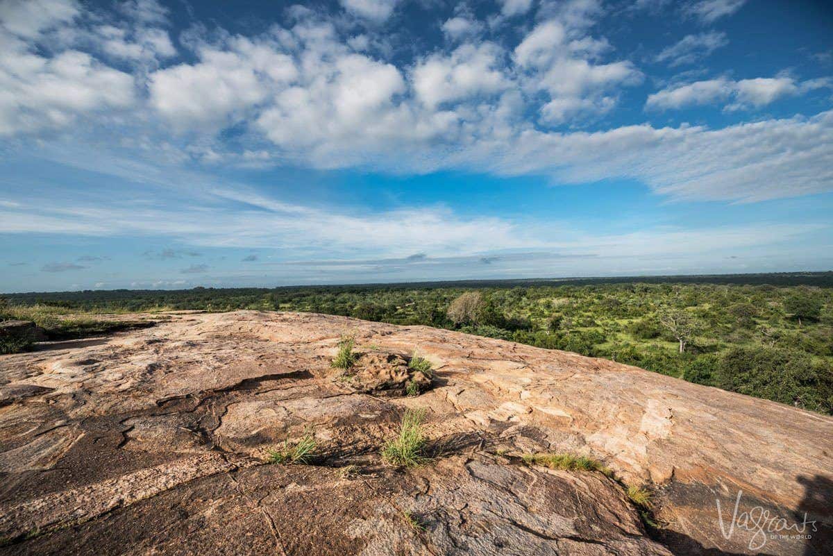 view across smooth rock outcrop onto the veld below.  Blue skies and moving cloud complete the picture in Kenya's best wildlife and wilderness destination, Laikipia