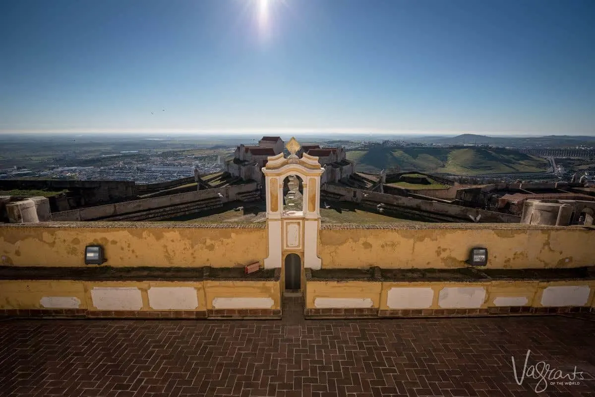looking down over yellow and white church onto the city of Evora.  Make a stop in Evora on your Alentejo road trip as evora is one of the best places to visit in alentejo portugal