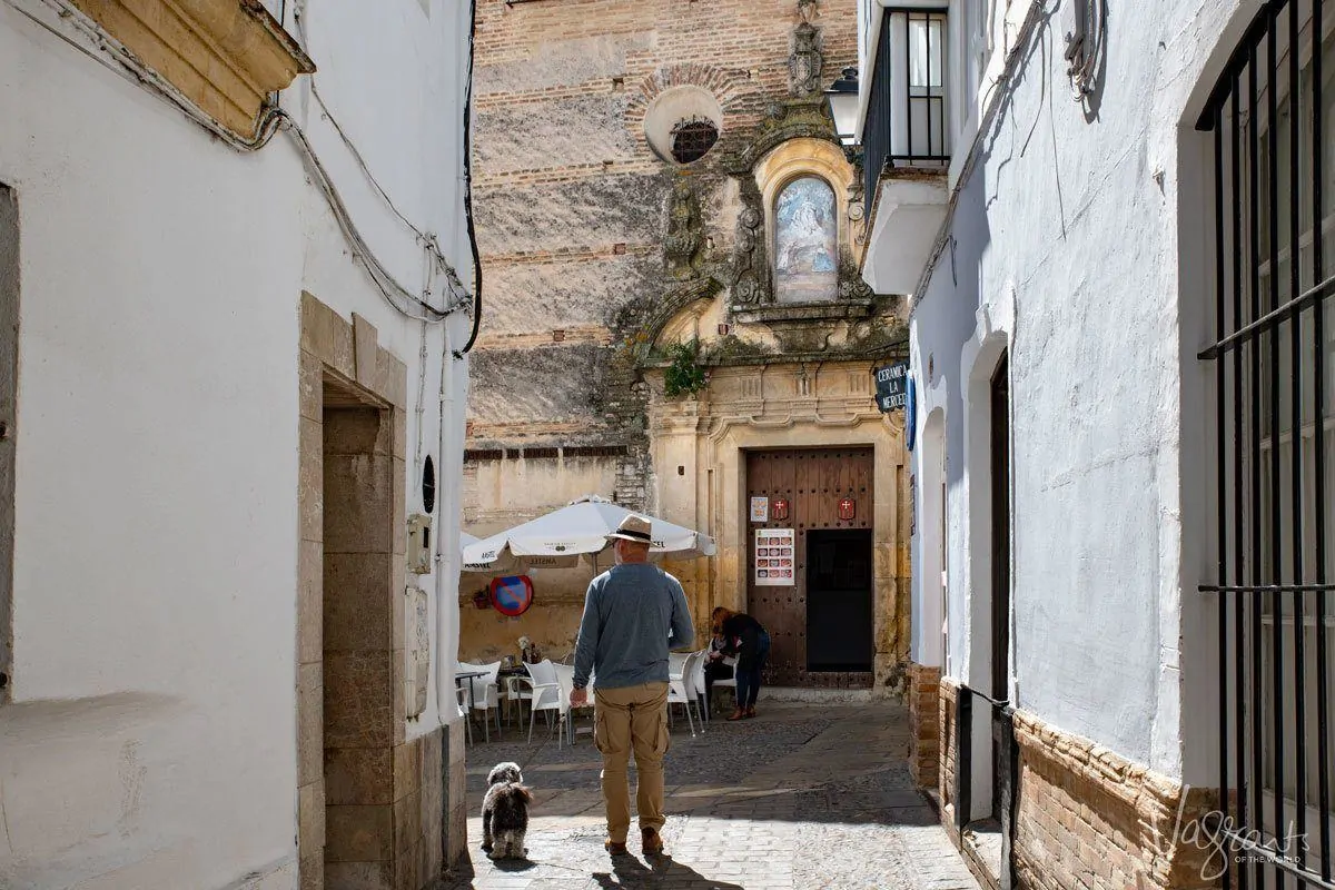 man in hat with dog outside a church during a tour of the white villages spain. 