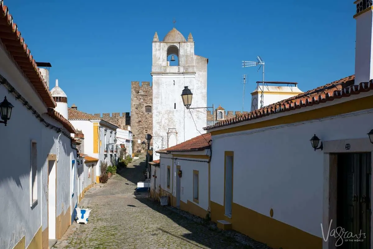 white and yellow walls of houses leading up to the terena castle.  we stopped here on our alentejo road trip and it was one of the best things we did.