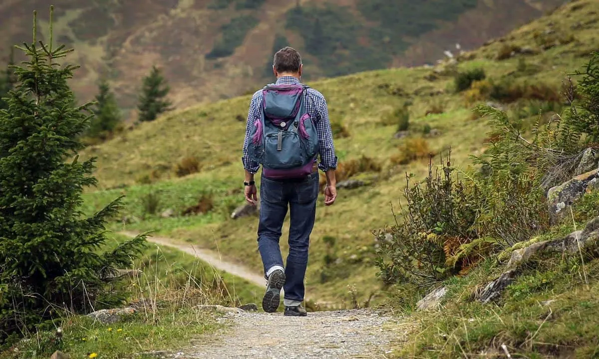 man with backpack walking along a country path on his self guided walking holiday UK