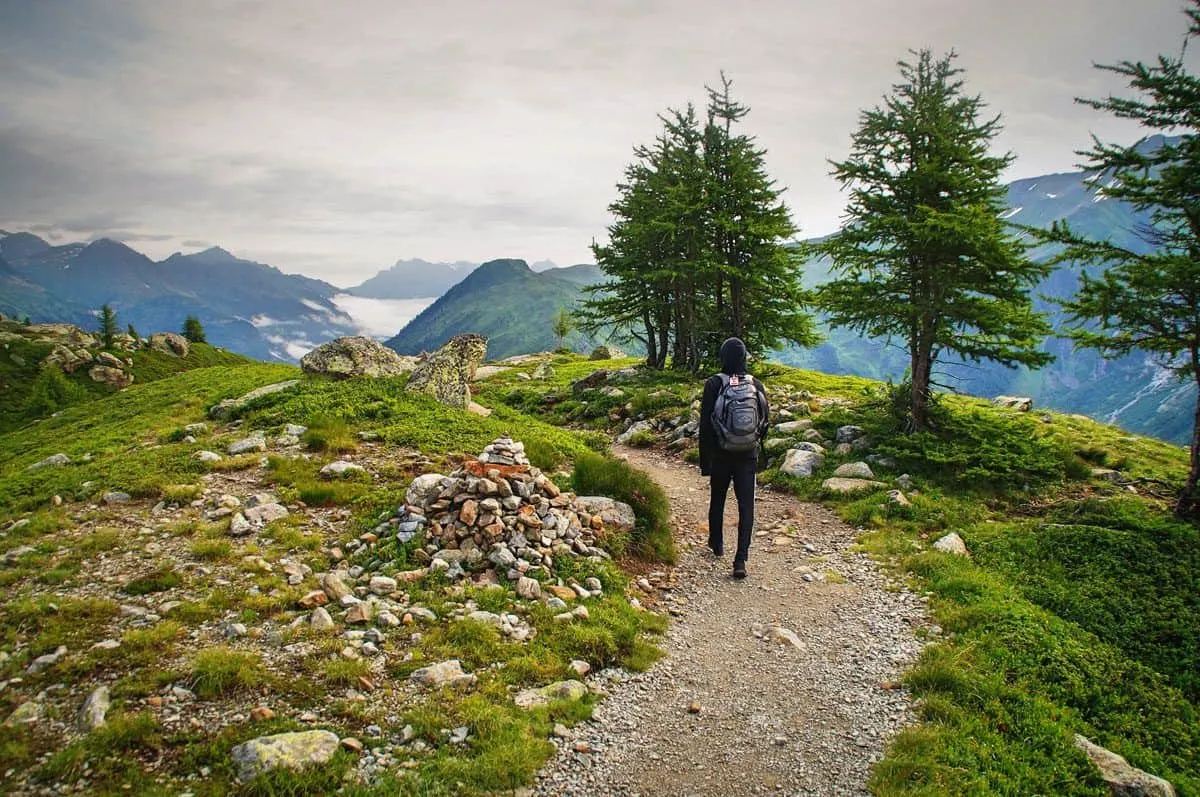 Person with backpack walking along a stony path high in the mountains.  Taking holidays on foot is very relaxing and rewarding.  A self guided trip also takes out some of the stress of organising your on foot holiday.