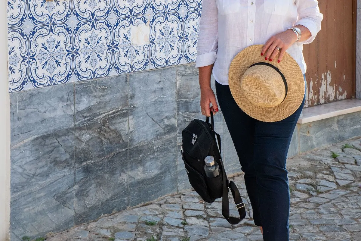 women holding a hat and backpack. this versatile womens travel backpack can be carried by the handle when not being worn on the back