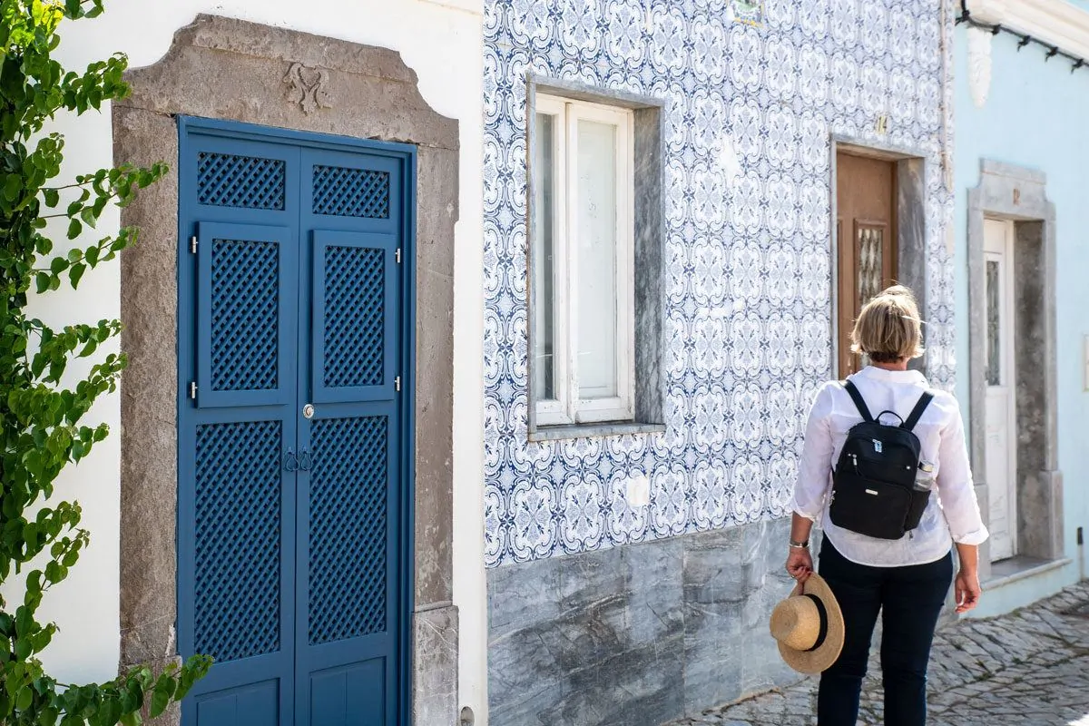 girl with black backpack outside a tiled walled house in Lisbon.  this style of backpack is a perfect womens travel backpack