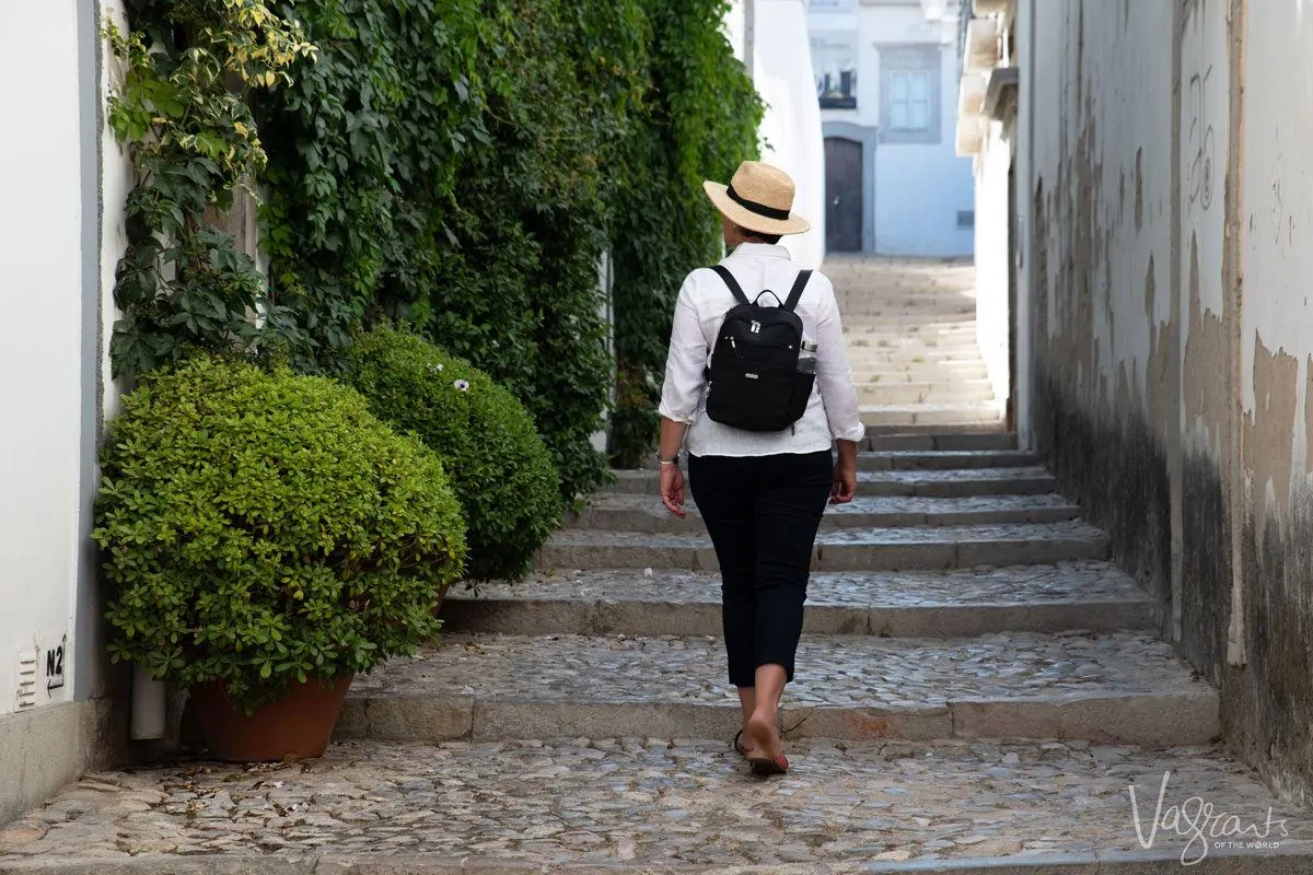 women walking along cobblestone street wearing black womens travel backpack.  combine this with baggallini's purses for travel and you have the perfect combo