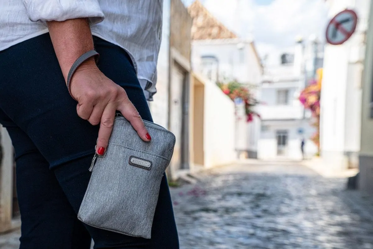 women holding a grey travel purse with wrist loop. these travel purses are best sellers