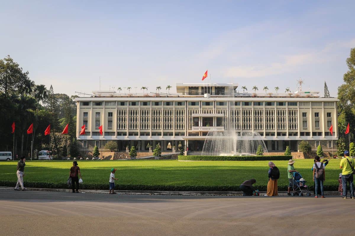 people, grass and fountain outside the reunification palace. one of the top things to do in Ho Chi Minh city is to visit the palace.