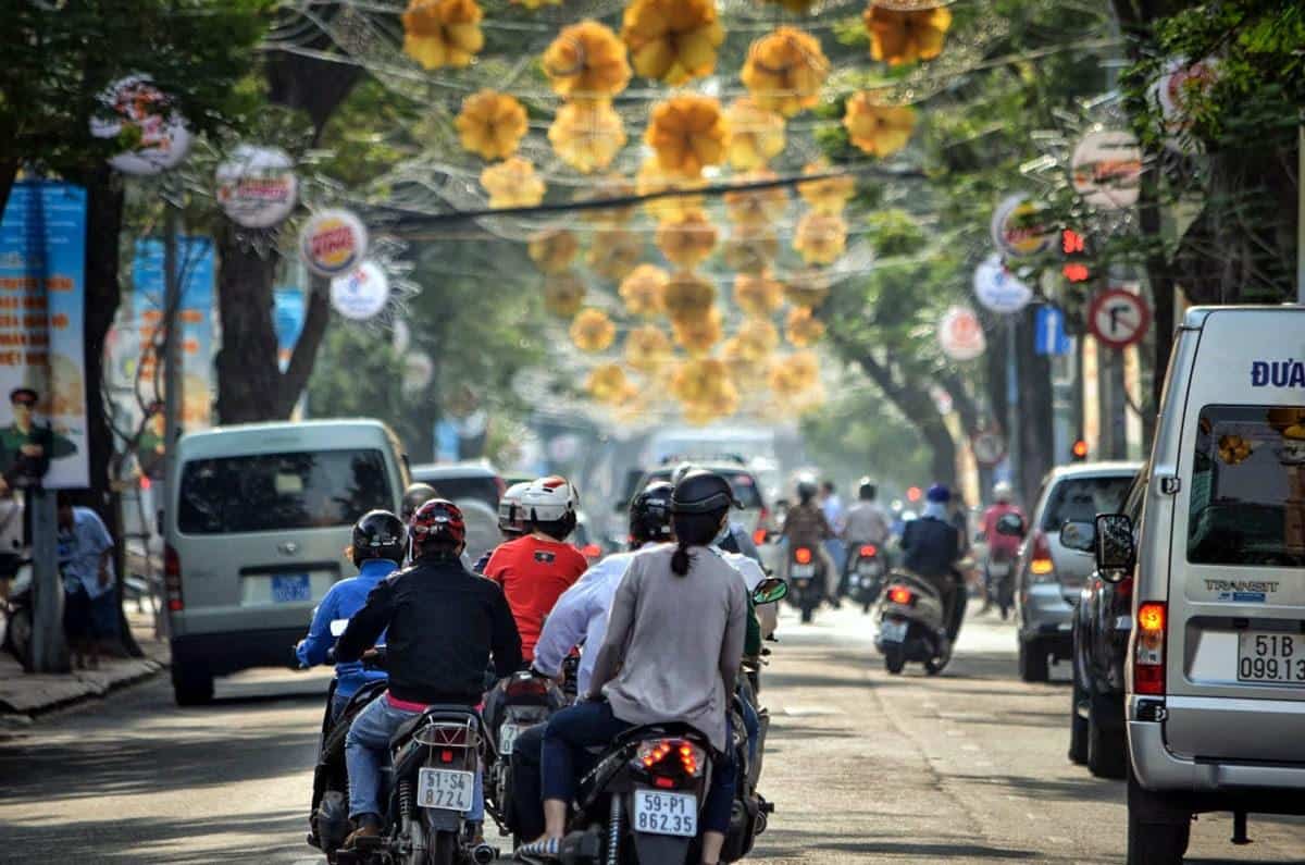 people riding scooters down a crowded street, driving in Saigon is one of the most interesting things to do in ho chi minh city