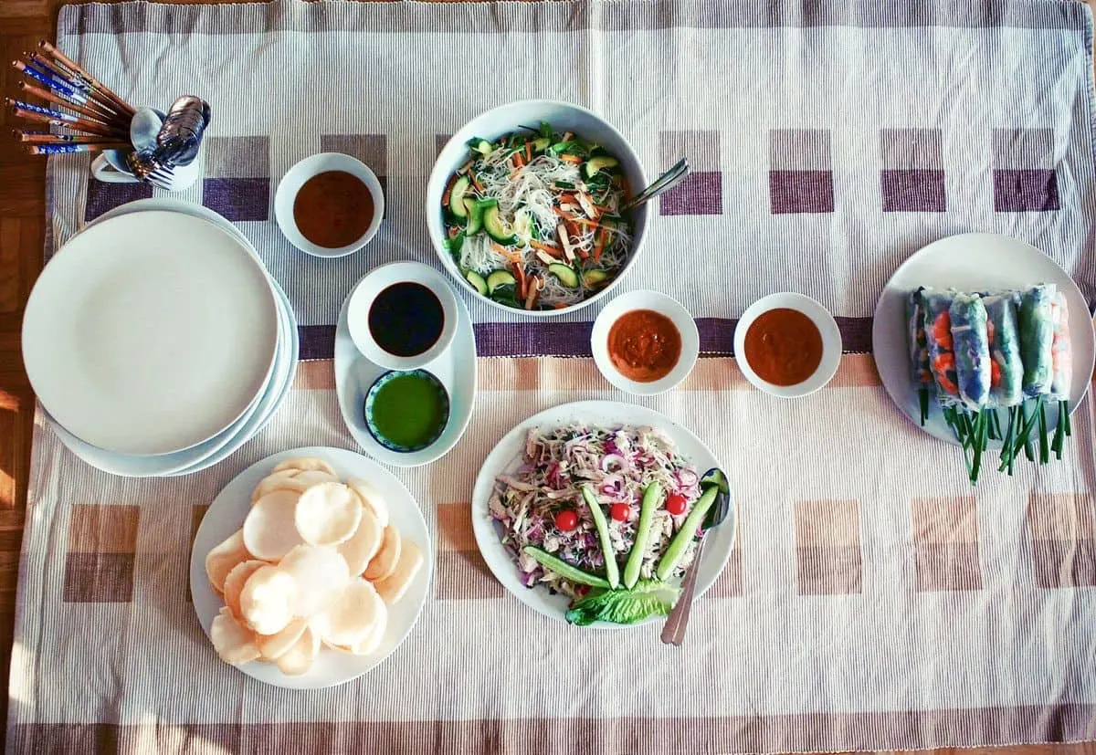 table laid out with vietnamese food and dipping sauces. the best food in ho chi minh city may well be what you buy at the markets and cook at home.