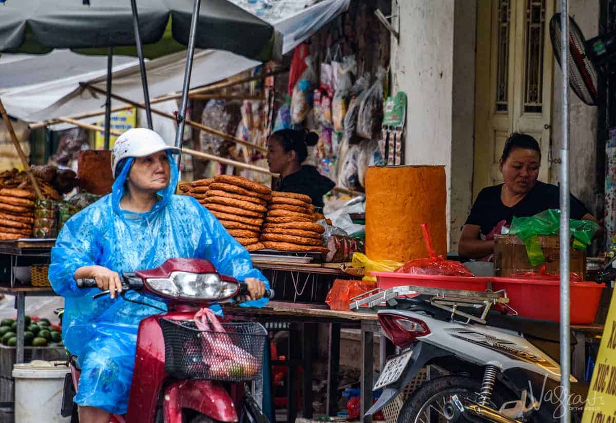 Lady on scooter outside street food stall, the best way to really enjoy Vietnamese street food is with a Hanoi Street Food Tour.