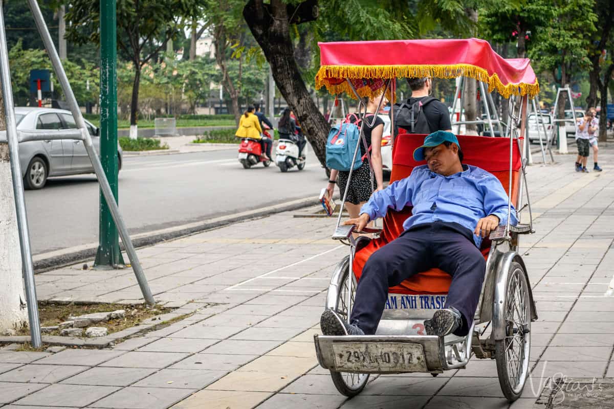 Man sleeping in a cyclo on the side of the street, a unique things to see in Hanoi Vietnam.